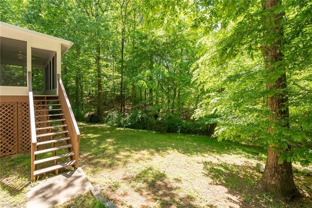 view of yard with a wooded view, stairway, and a sunroom