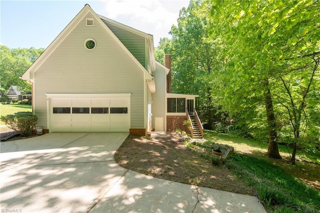view of front of property with driveway, a chimney, stairs, and a sunroom