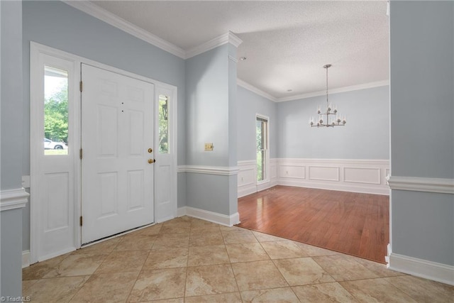 foyer with ornamental molding, an inviting chandelier, and light tile patterned floors