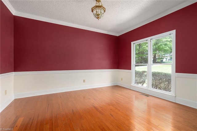 unfurnished room featuring a textured ceiling, crown molding, visible vents, hardwood / wood-style floors, and an inviting chandelier