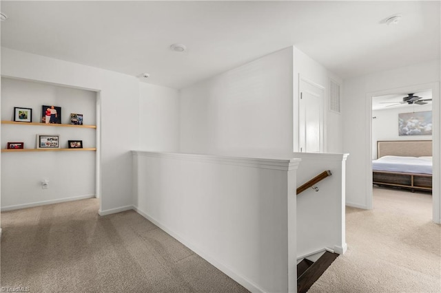 hall featuring carpet floors, baseboards, an upstairs landing, and visible vents