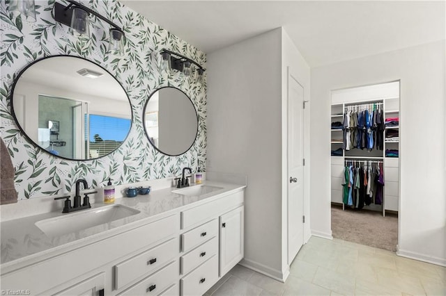 bathroom featuring a sink, baseboards, wallpapered walls, and double vanity