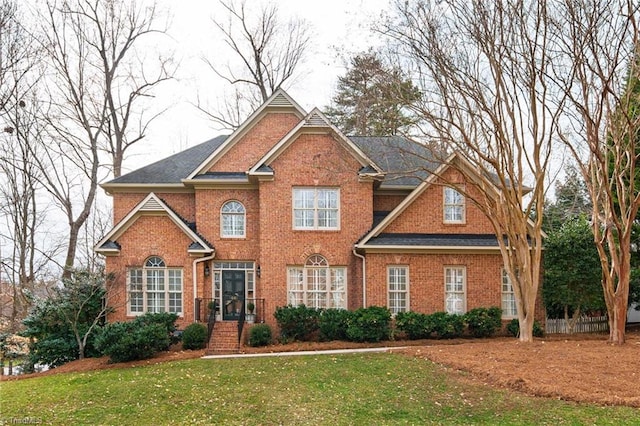 view of front of property with brick siding, a front yard, and fence