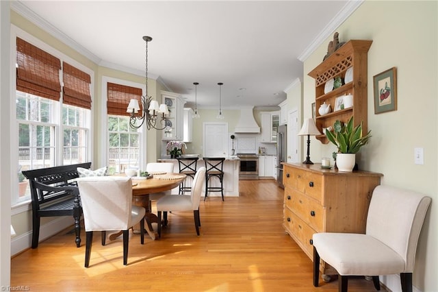 dining area with a notable chandelier, crown molding, and light wood-style floors