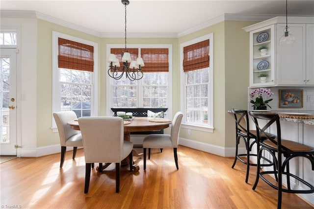 dining space featuring a healthy amount of sunlight, a notable chandelier, light wood-style floors, and ornamental molding