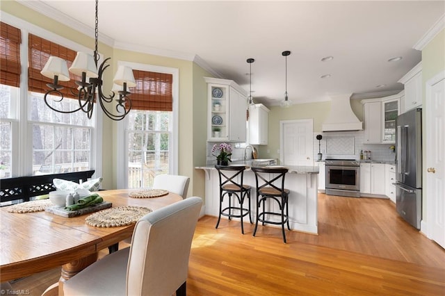 dining area featuring light wood-style flooring and crown molding