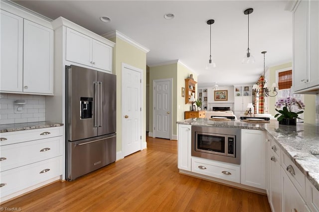 kitchen featuring a peninsula, stainless steel appliances, white cabinetry, crown molding, and light wood-type flooring