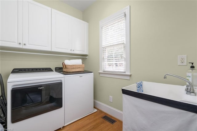 laundry area featuring baseboards, visible vents, light wood finished floors, washing machine and clothes dryer, and cabinet space