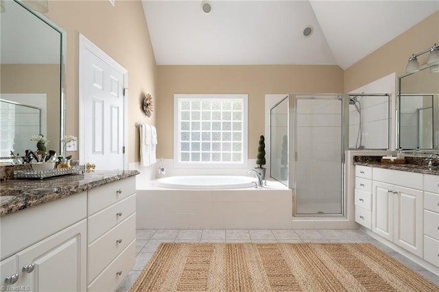 bathroom featuring two vanities, vaulted ceiling, a shower stall, a garden tub, and tile patterned floors