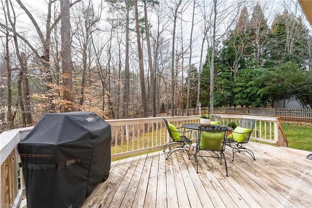 wooden terrace with outdoor dining space, fence, and grilling area