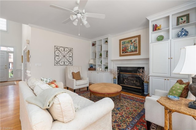 living area with ceiling fan, a premium fireplace, ornamental molding, and light wood finished floors