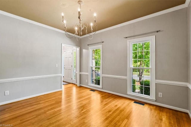 unfurnished room featuring an inviting chandelier, baseboards, wood finished floors, and visible vents