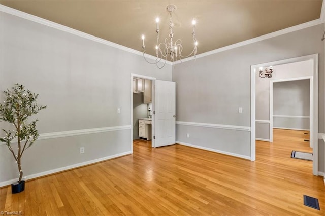 empty room featuring visible vents, ornamental molding, a chandelier, and light wood-type flooring