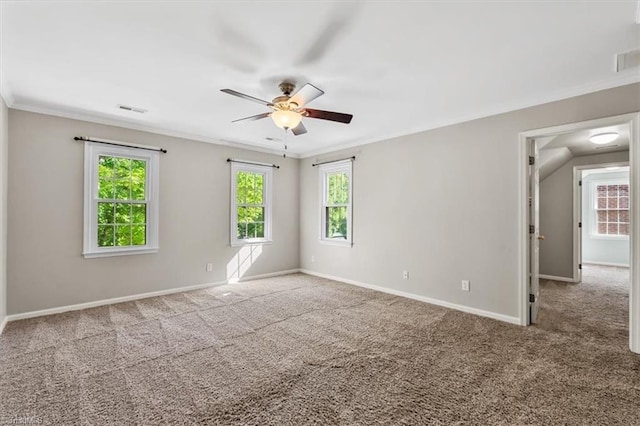 spare room featuring crown molding, carpet, a ceiling fan, baseboards, and visible vents