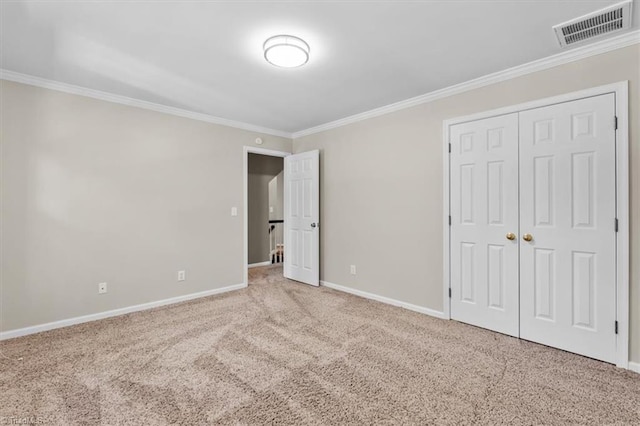 unfurnished bedroom featuring crown molding, carpet floors, baseboards, visible vents, and a closet