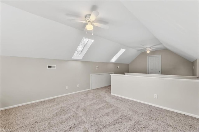 bonus room featuring visible vents, baseboards, lofted ceiling with skylight, ceiling fan, and carpet