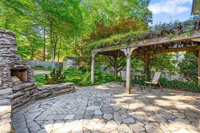 view of patio with an outdoor stone fireplace, a fenced backyard, outdoor dining area, a storage shed, and an outbuilding