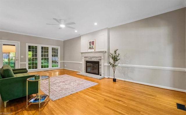 living area with crown molding, ceiling fan, visible vents, and wood finished floors