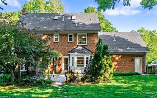 back of property with a lawn, a patio, a chimney, and brick siding