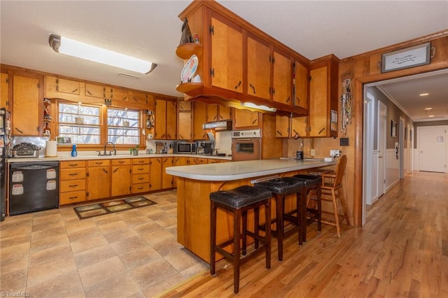 kitchen with stainless steel appliances, light hardwood / wood-style floors, kitchen peninsula, a breakfast bar area, and crown molding