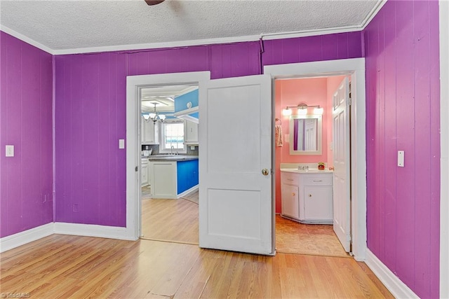 unfurnished bedroom featuring crown molding, connected bathroom, sink, and light hardwood / wood-style flooring