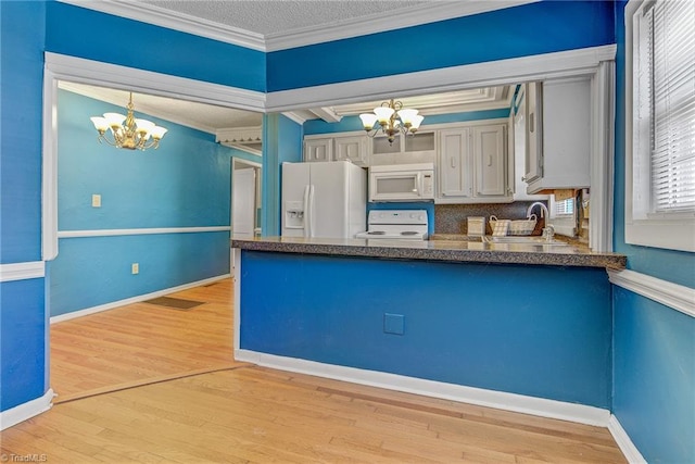 kitchen featuring white appliances, pendant lighting, a chandelier, light hardwood / wood-style flooring, and ornamental molding