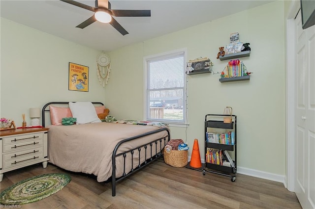 bedroom featuring a ceiling fan, baseboards, and wood finished floors