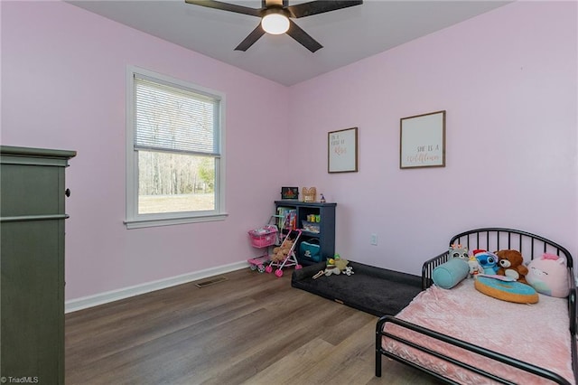 bedroom featuring visible vents, a ceiling fan, baseboards, and wood finished floors