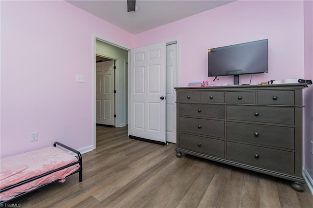 bedroom with a ceiling fan, wood finished floors, and baseboards