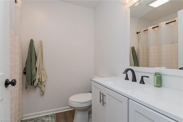 bathroom with vanity, wood finished floors, baseboards, curtained shower, and toilet