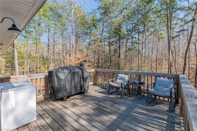 wooden terrace with grilling area and a wooded view