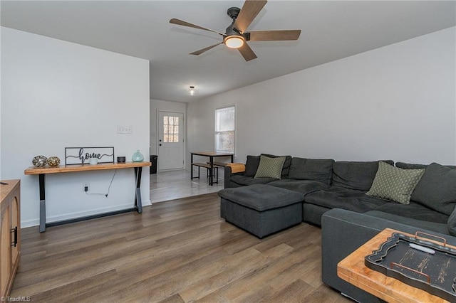 living room with baseboards, ceiling fan, and wood finished floors