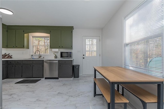 kitchen featuring a sink, light countertops, appliances with stainless steel finishes, green cabinets, and marble finish floor