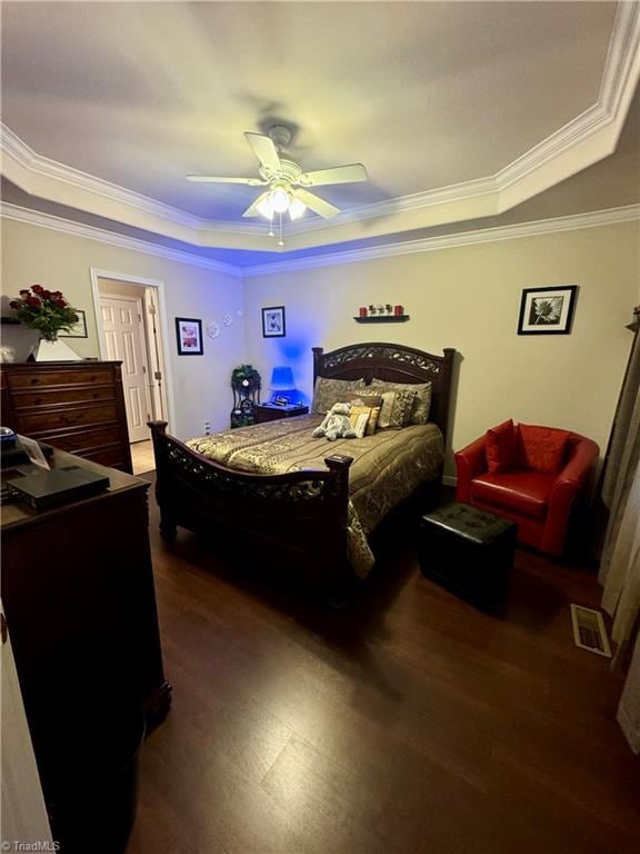 bedroom with a raised ceiling, ceiling fan, crown molding, and dark wood-type flooring