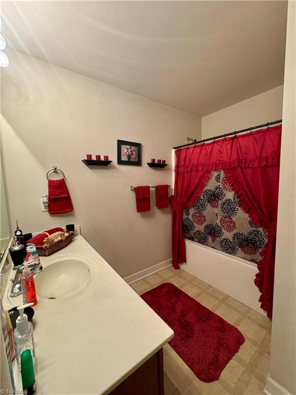 bathroom featuring vanity and shower / bathtub combination with curtain