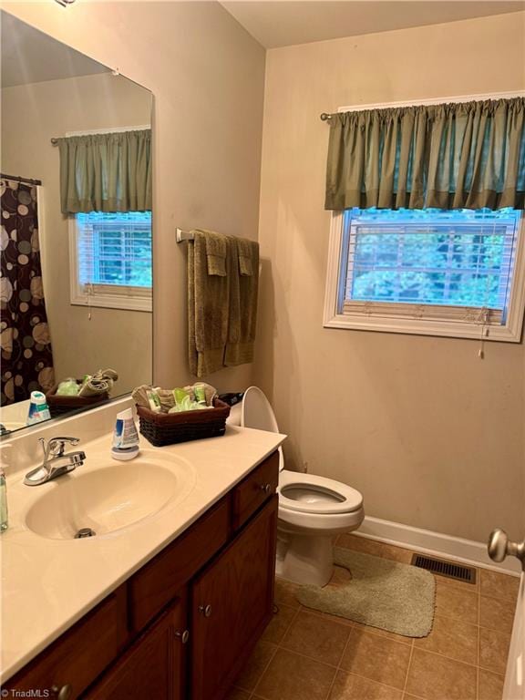 bathroom with tile patterned floors, a wealth of natural light, vanity, and toilet