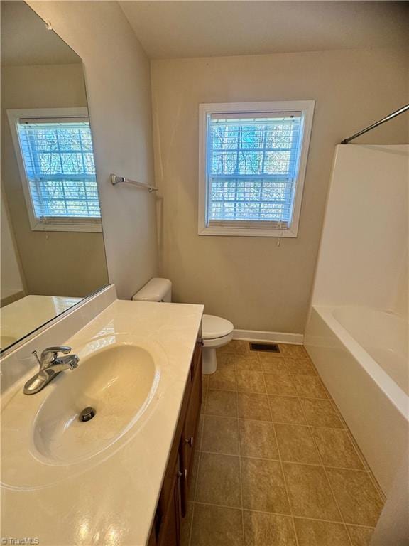 bathroom with tile patterned flooring, plenty of natural light, toilet, and vanity