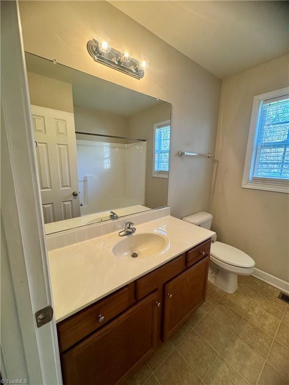 bathroom with a shower, vanity, tile patterned floors, and toilet