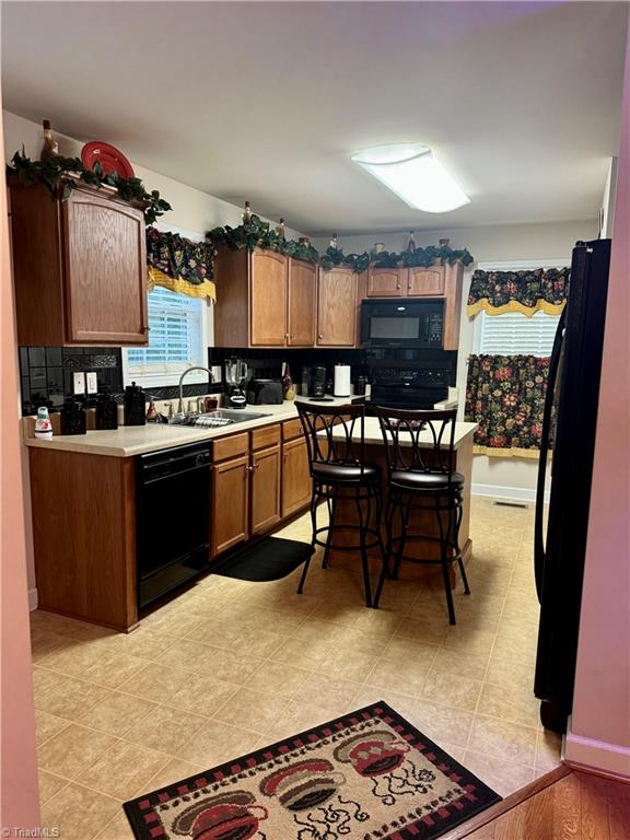 kitchen featuring light tile patterned floors, sink, tasteful backsplash, and black appliances