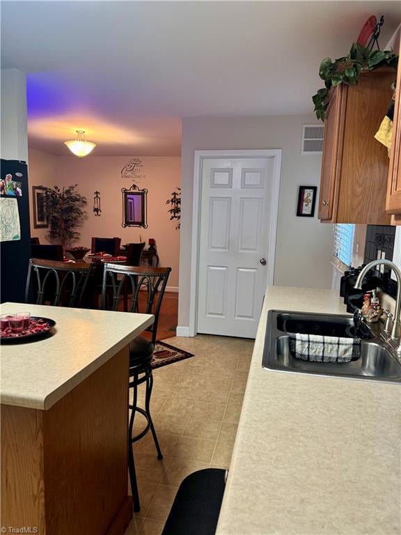 kitchen with a breakfast bar, sink, and light tile patterned flooring