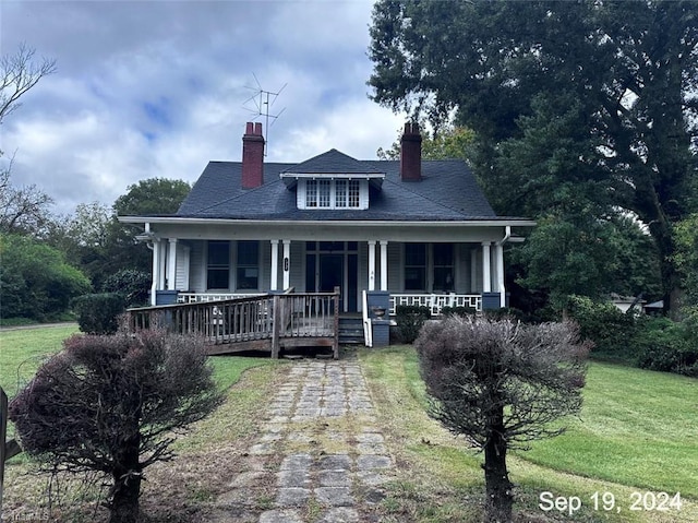 bungalow-style house featuring covered porch and a front yard