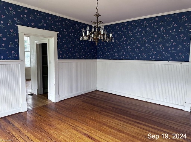 unfurnished dining area with ornamental molding, hardwood / wood-style flooring, and an inviting chandelier