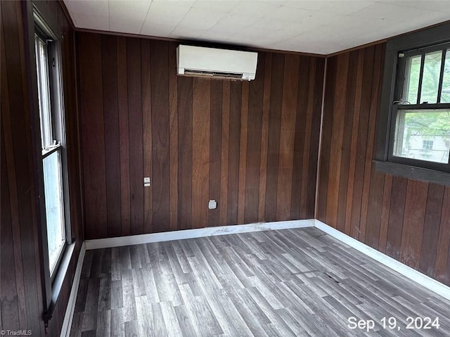 empty room featuring a wall unit AC, wood walls, and hardwood / wood-style floors