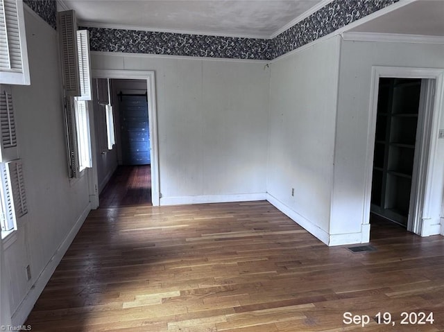 empty room featuring crown molding and dark wood-type flooring