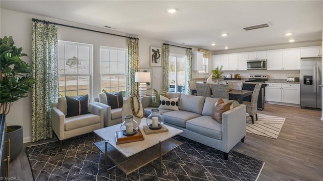 living room with dark wood finished floors, visible vents, and recessed lighting