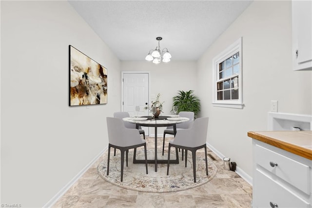 dining area with a textured ceiling and an inviting chandelier