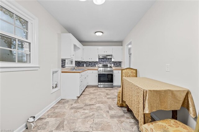 kitchen featuring backsplash, exhaust hood, sink, stainless steel range oven, and white cabinets