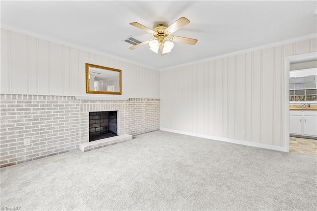 unfurnished living room with light carpet, ceiling fan, ornamental molding, and brick wall