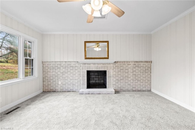 unfurnished living room with carpet, a brick fireplace, ornamental molding, and wood walls