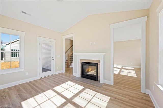 1087 Fairhaven Dr Lot 48, Mebane, NC 27302 - unfurnished living room featuring light wood-style flooring, lofted ceiling, a glass covered fireplace, and baseboards